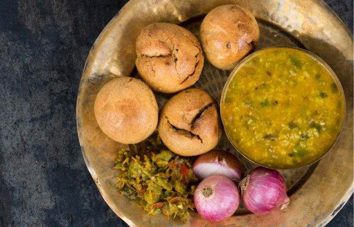 Traditional Indian Rajasthani meal of Dal Baati Churma served on a plate with ghee, chutney, and pickle on the side
