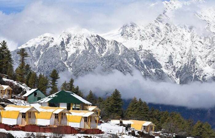 Scenic winter view of snow-covered Auli slopes with pine trees and a cable car in the background, perfect for a Himalayan ski getaway.